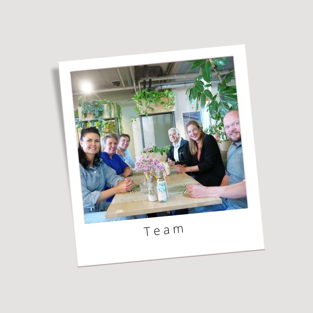 Het team van Geven is leuker zit samen rond een tafel op kantoor